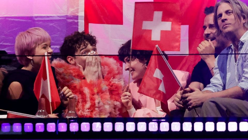 Gruppe von Menschen mit Schweizer Flaggen freut sich bei einem Event.