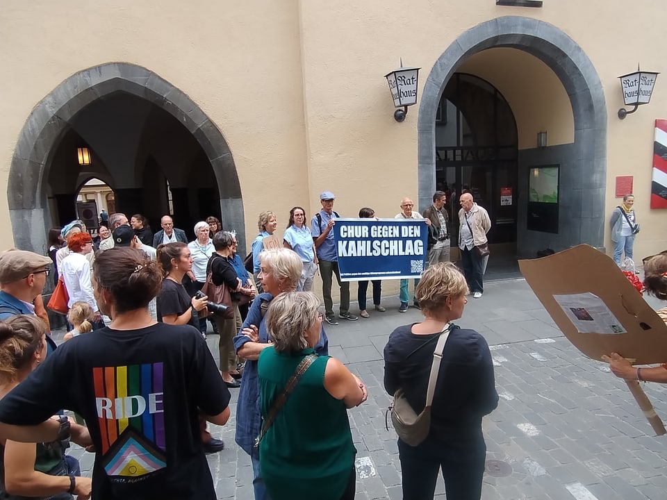 Menschen versammeln sich mit einem Banner bei einem Protest in Chur.