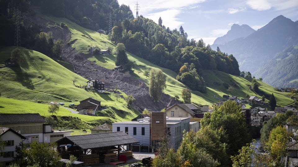 Dorf mit Bergrutsch im Hintergrund.