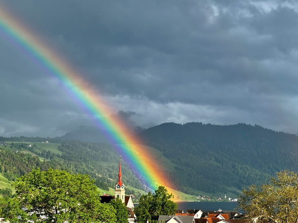 Regenbogen über einem Berg und einer Kirche.