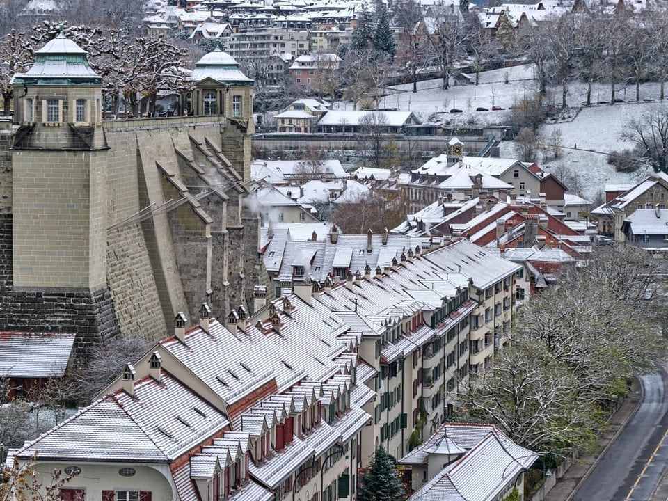 Verschneite Stadtansicht mit alten Gebäuden und Burgmauer.