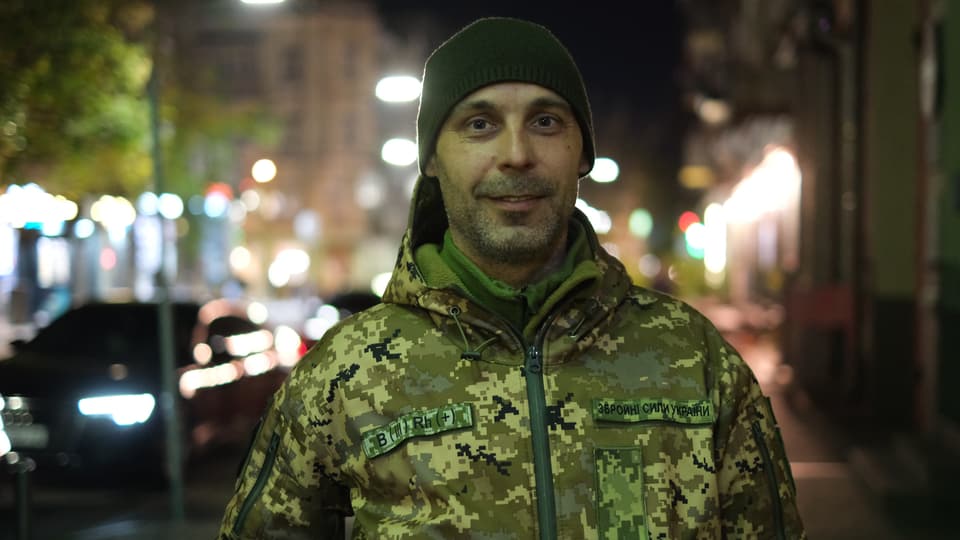Mann in Militäruniform gekleidet lächelt in Kamera