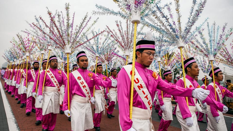 Parade in Kuala Lumpur mit rosa Uniformen und Bäumen aus Lametta