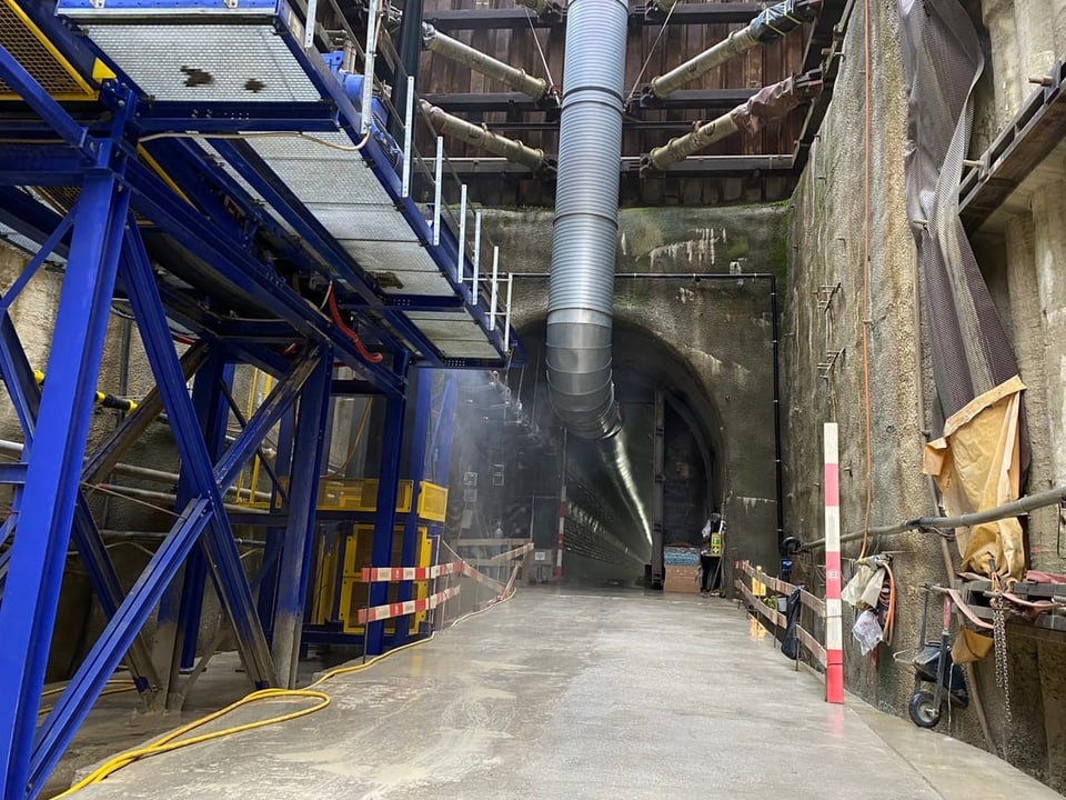 Tunnelbaustelle mit grossen Lüftungsrohren und Metallgerüst.