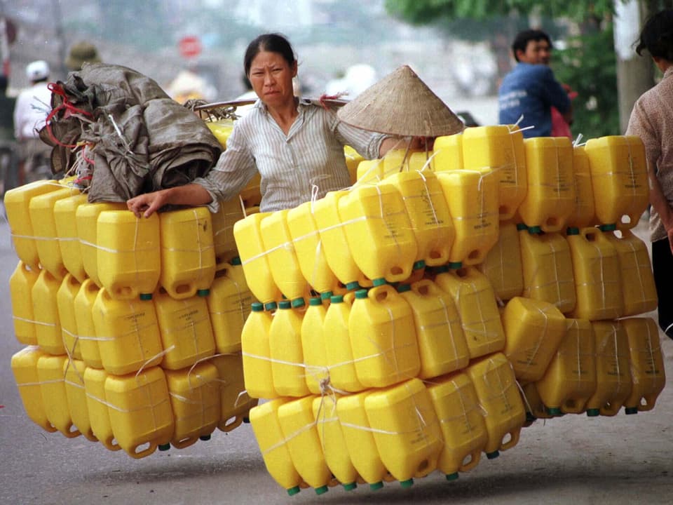 Frau trägt viele Plastikbehälter in Vietnam.