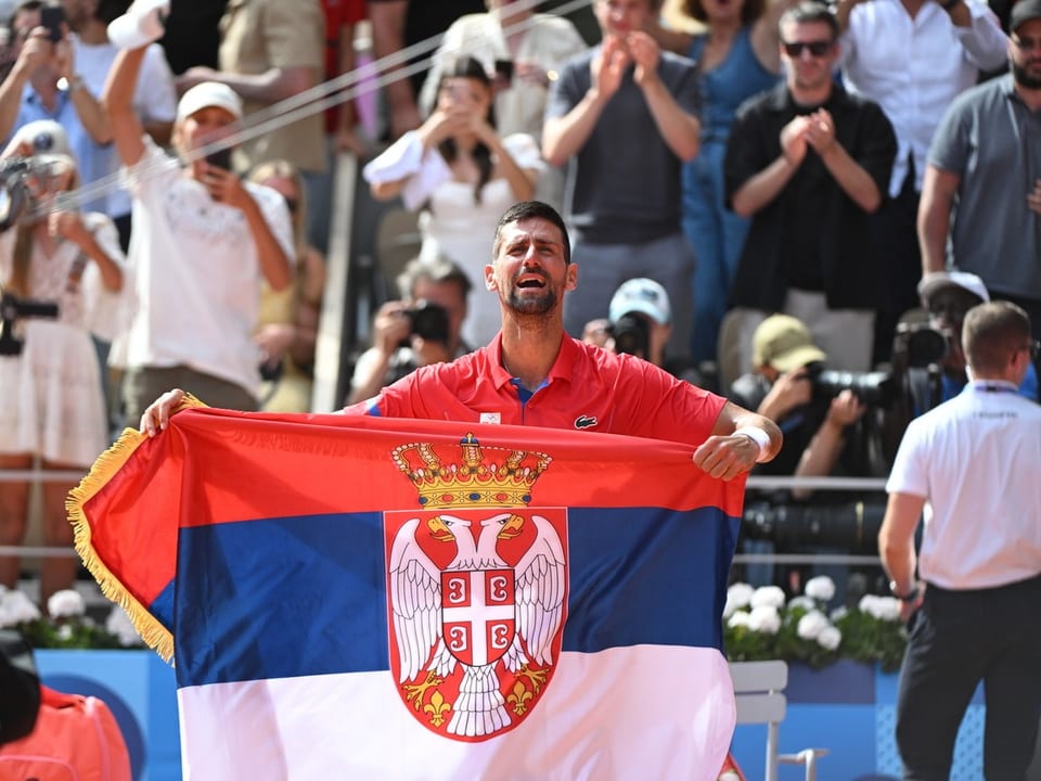 Mann mit serbischer Flagge bei einem Tennis-Event.