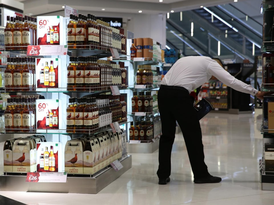 Ein Mann steht vor einem Regal in einem Laden und sucht ein Produkt.