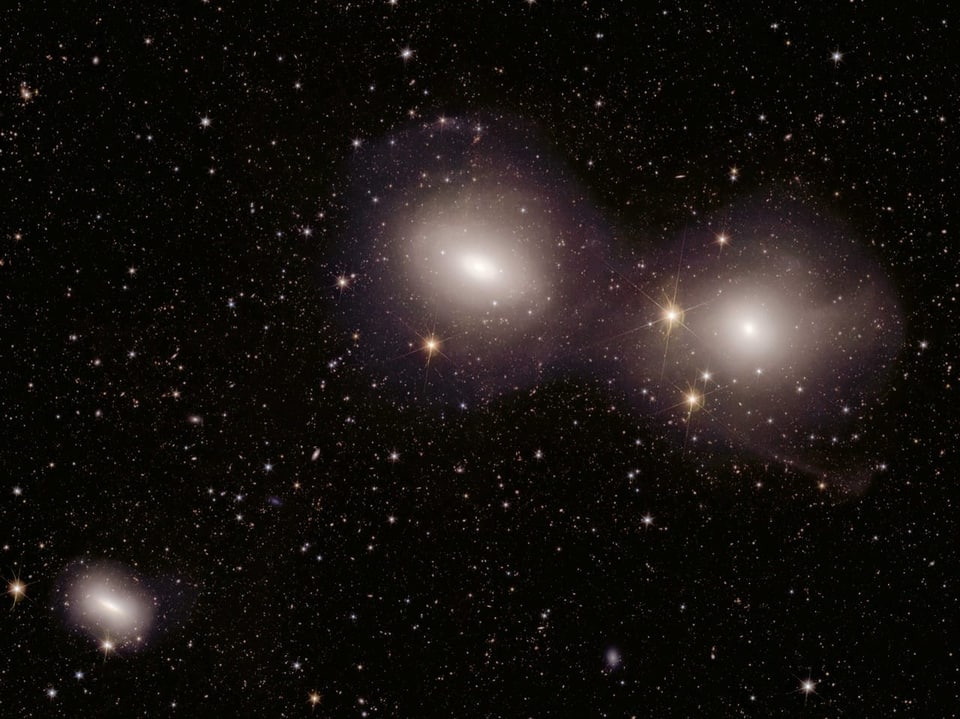 Three galaxies and stars in space.
