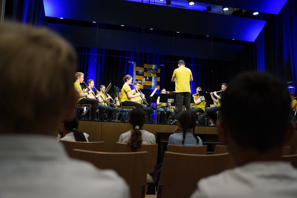 Junge Zuschauer im Publikum beobachten die Musikanten auf der Bühne.