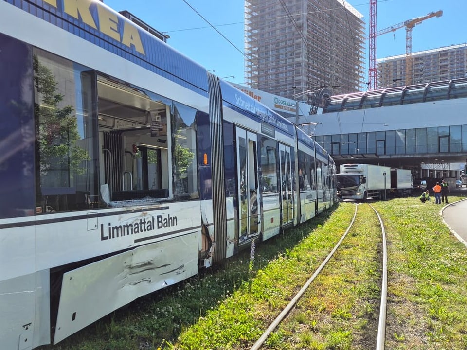 Ein Tram, das auf der Seite grössere Schäden aufweist, weiter hinten ein Lastagen, der mit dem Tram kollidiert ist. 