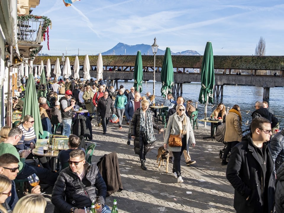 Leute schlendern in Luzern der Reuss entlang.