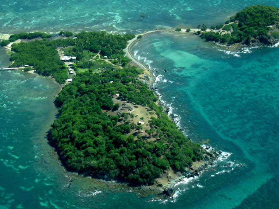 Insel von oben mit grüner Vegetation und umliegendem Ozean.