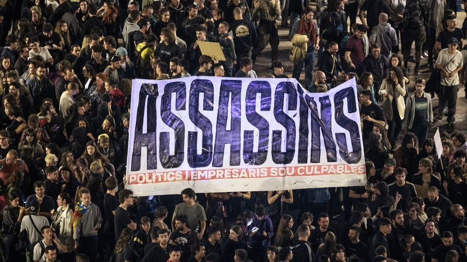 Menschenmenge mit Banner 'ASSASSINS'.