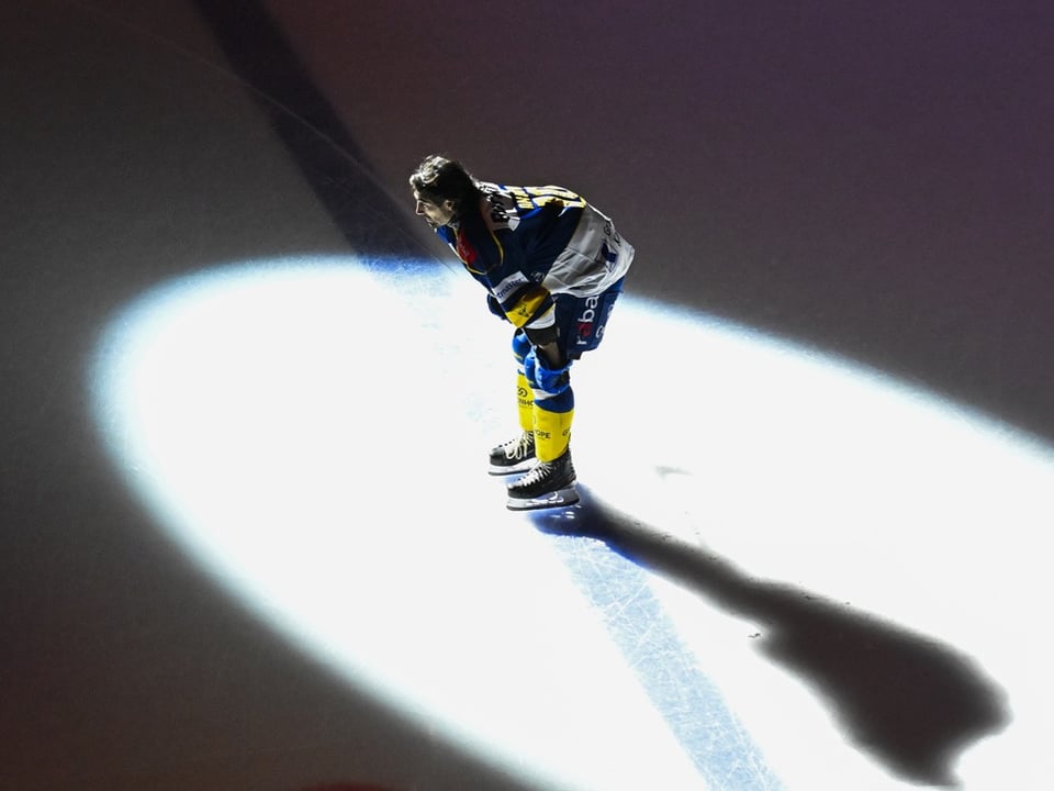 Eishockeyspieler steht im Spotlight auf der Eisfläche.