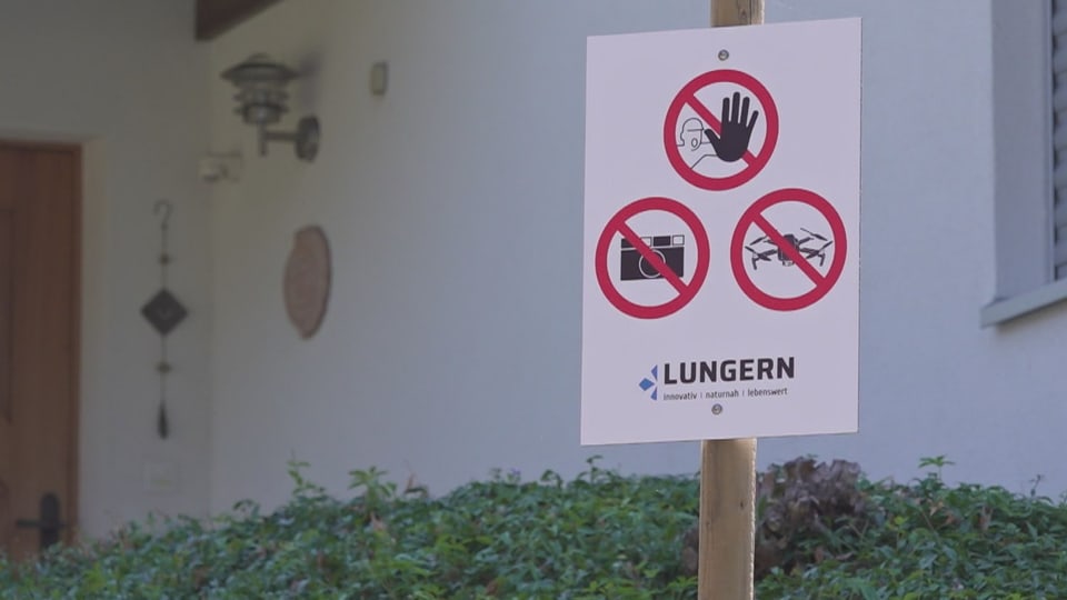 Weisses Schild mit Verbotszeichen vor einem Haus.