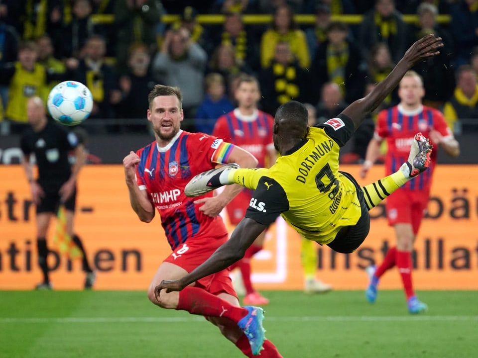 Fussballspieler in rotem Trikot und gelbem Trikot im Spiel auf dem Feld.