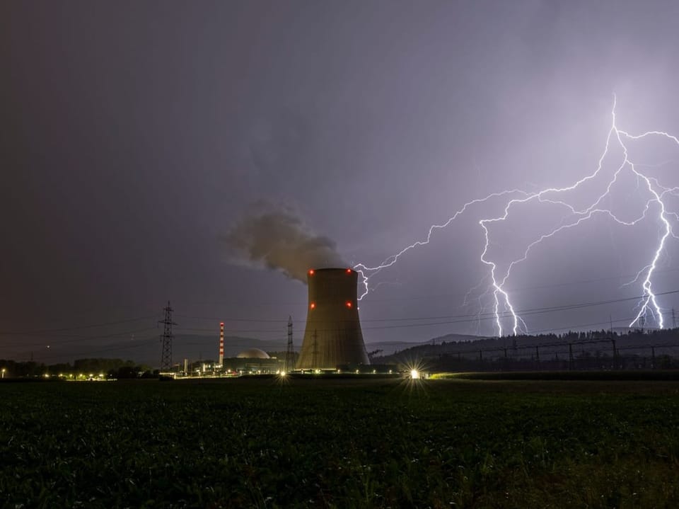 Blitzeinschläge hinter dem Kühlturm eines AKW.