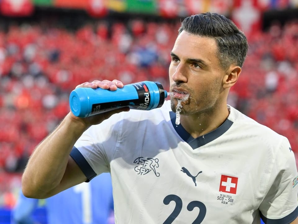 Schweizer Fussballspieler trinkt aus einer Wasserflasche.