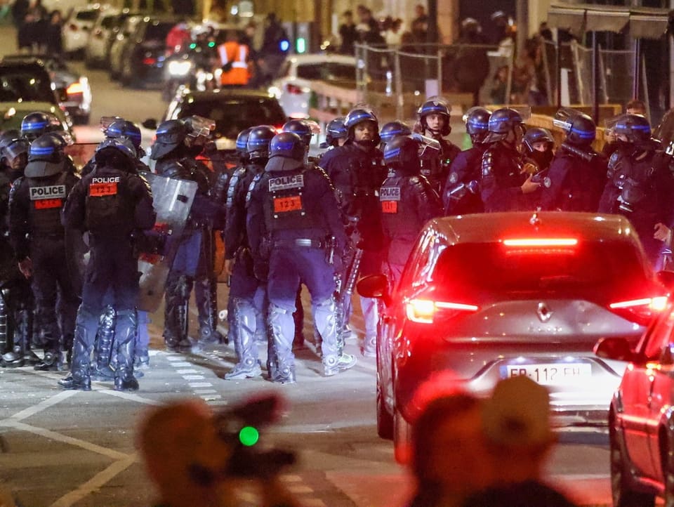 Eine grosse Gruppe von Einsatzpolizisten stehen auf einer Strasse.