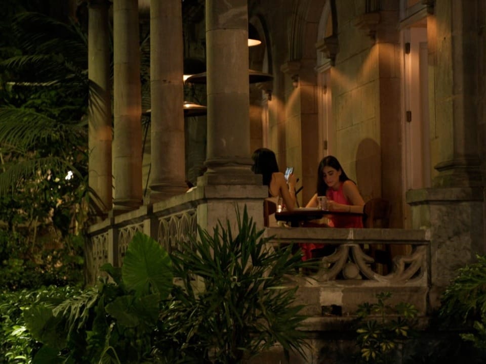 Zwei Frauen sitzen bei Nacht auf einer Veranda und lesen.