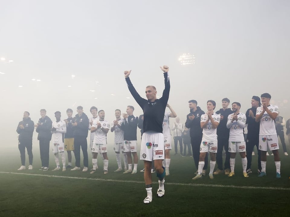 Fussballspieler feiert auf dem Spielfeld im Nebel.