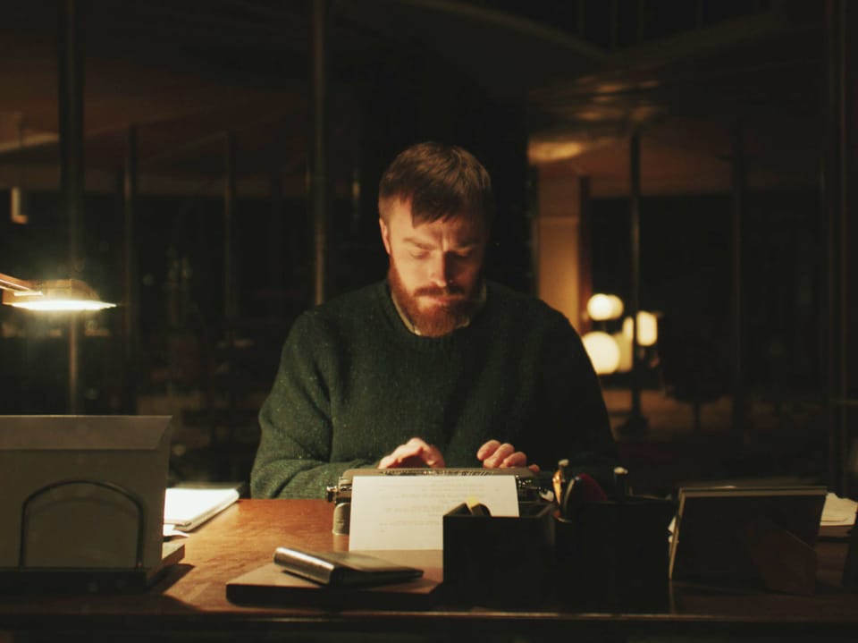 Ein Mann schreibt in der Nacht auf einer alten Schreibmaschine.