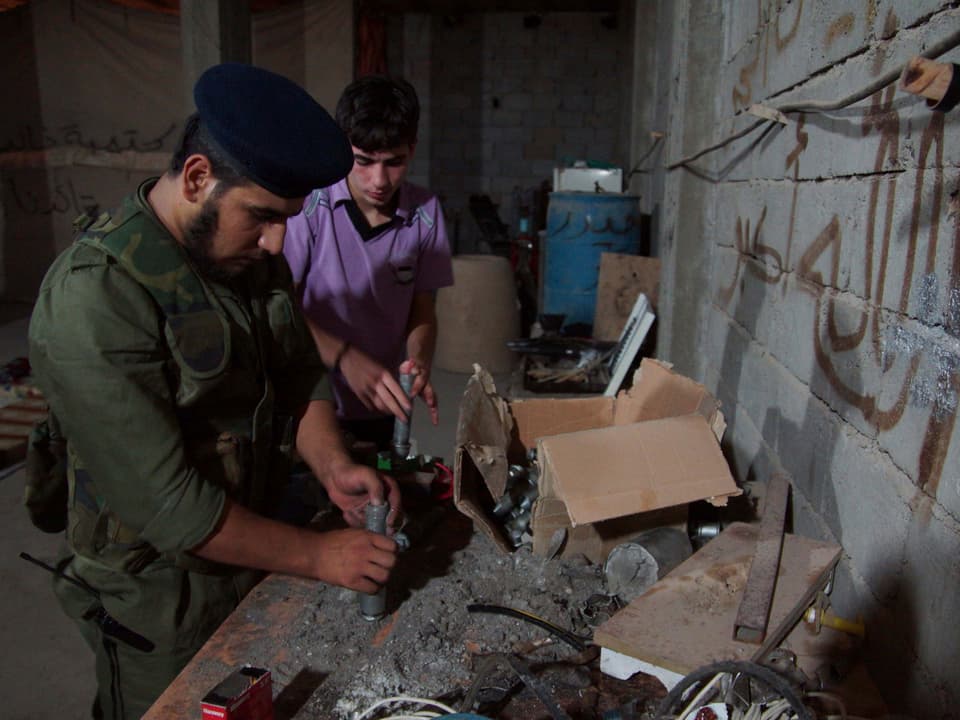Ein Kämpfer der Freien Syrischen Armee füllt zusammen mit einem Jugendlichen Sprengstoff in ein Metallrohr.