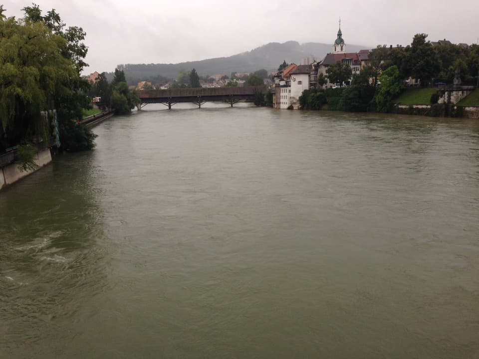 Ein Fluss mit hohem Wasserstand, in der Ferien eine Brücke und eine Stadt