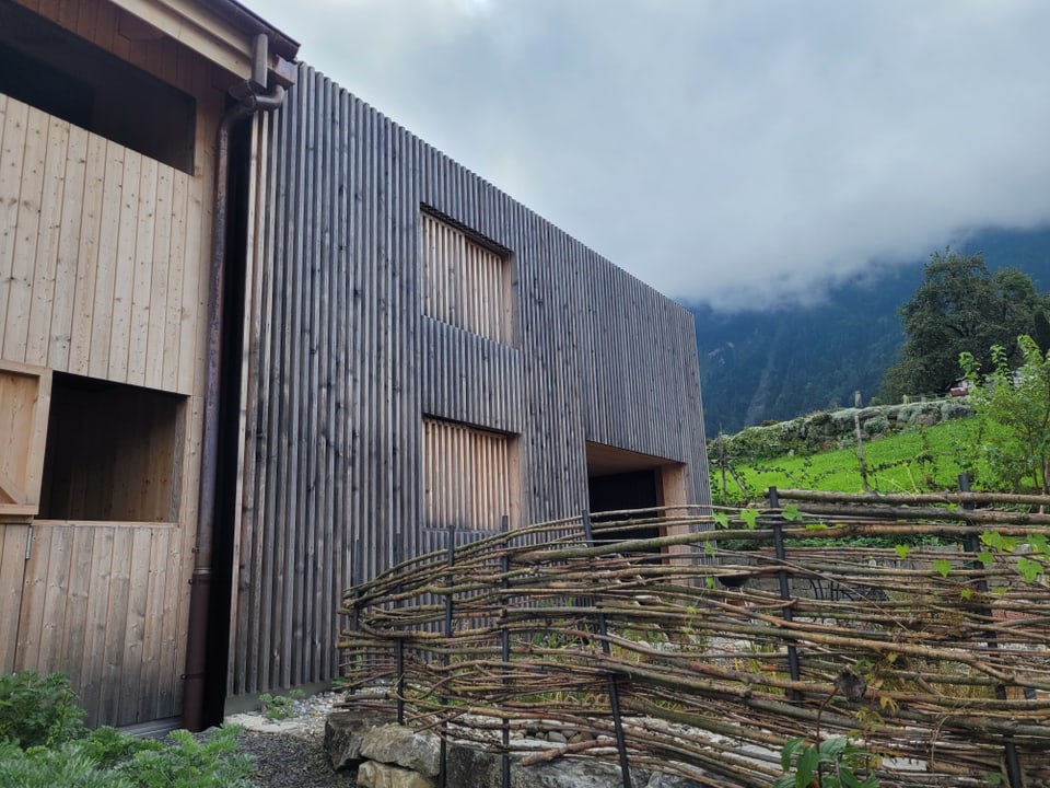 Sicht auf die Fassade: links der historische Hausteil, rechts ein moderner Anbau. Alles in Holz.