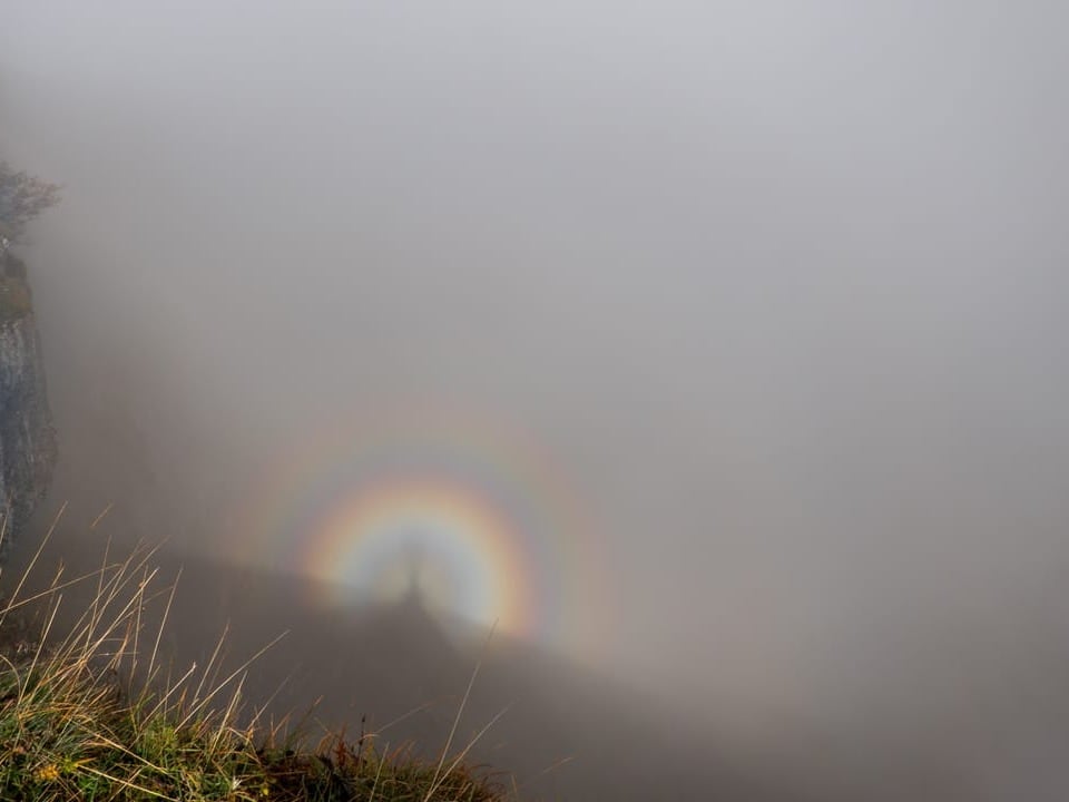 Bergsteiger-Schattenspiel im Nebel mit Regenbogen.