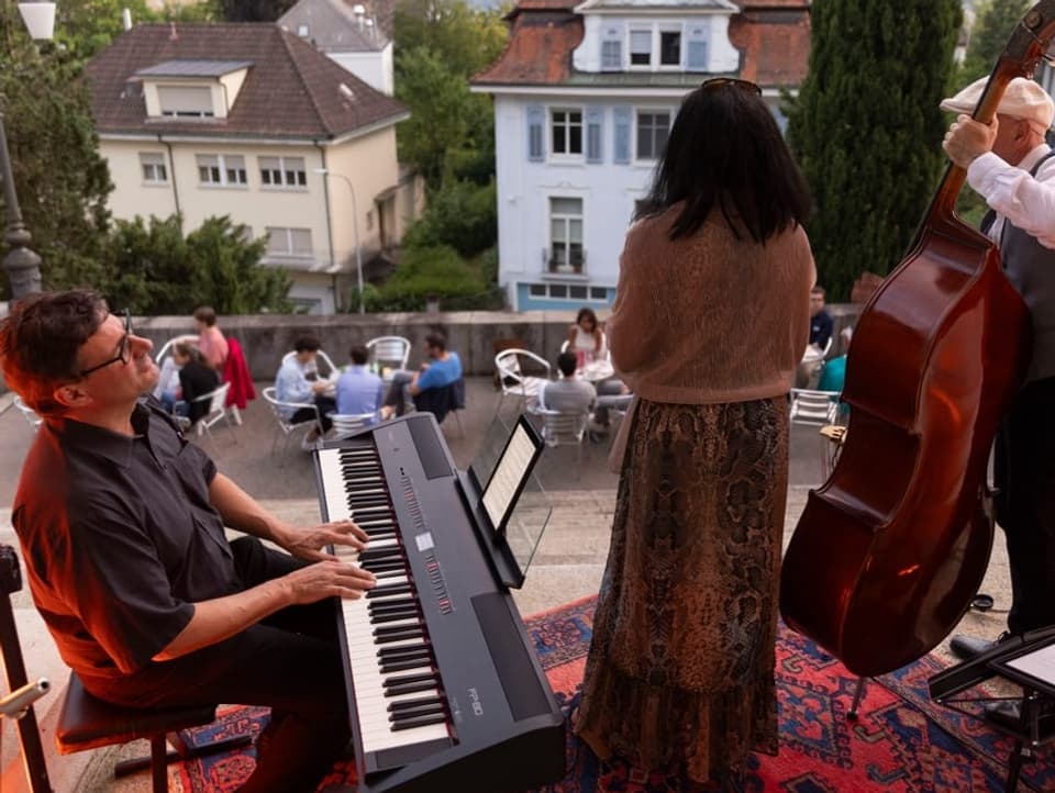 Eine Band mit Keyboard, Bass und Sängerin spielt live Musik.