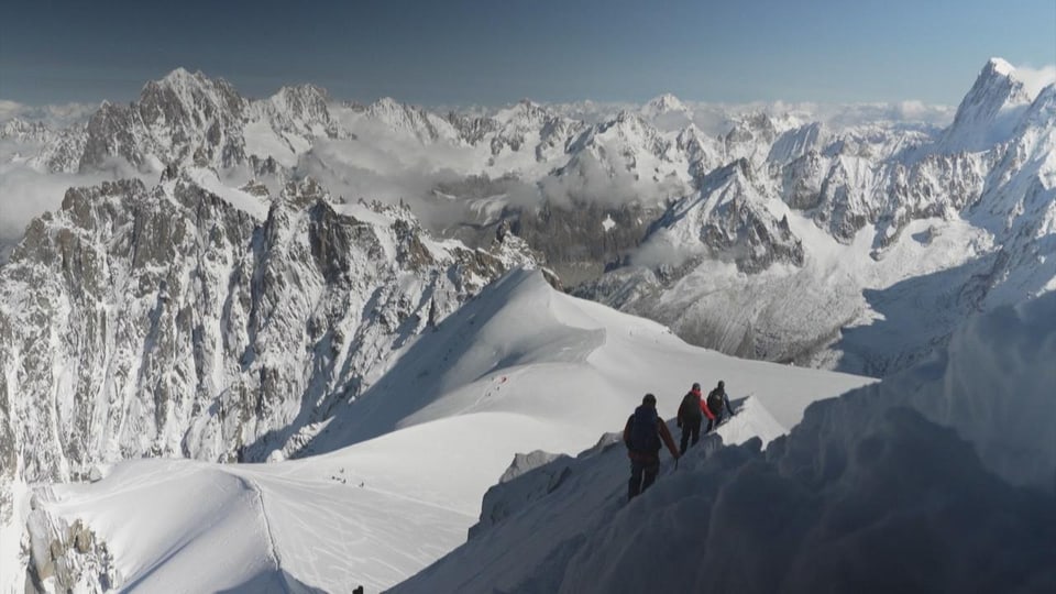 Eine Gruppe Bergsteiger beim Abstieg auf einem schneebedeckten Berggrad. 