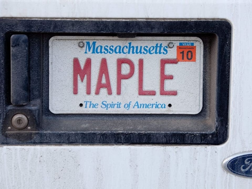 Nahaufnahme eines Massachusetts-Kennzeichens mit dem Text 'MAPLE' an einem Ford.