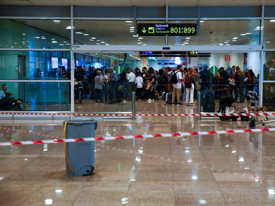 Wartende Menschenmenge am Flughafen hinter Absperrband.