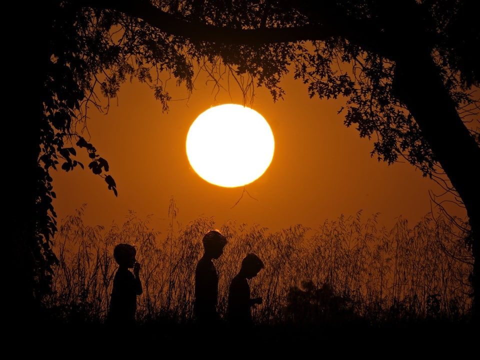 Kinder vor einem Sonnenuntergang.