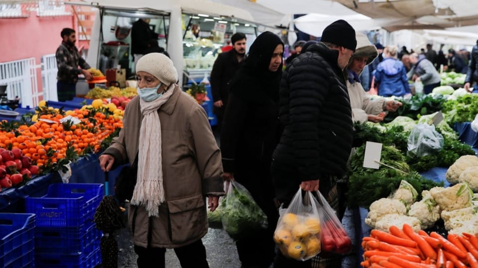 Menschen auf einem Markt in Istanbul, der Gemüse und Früchte anbietet.