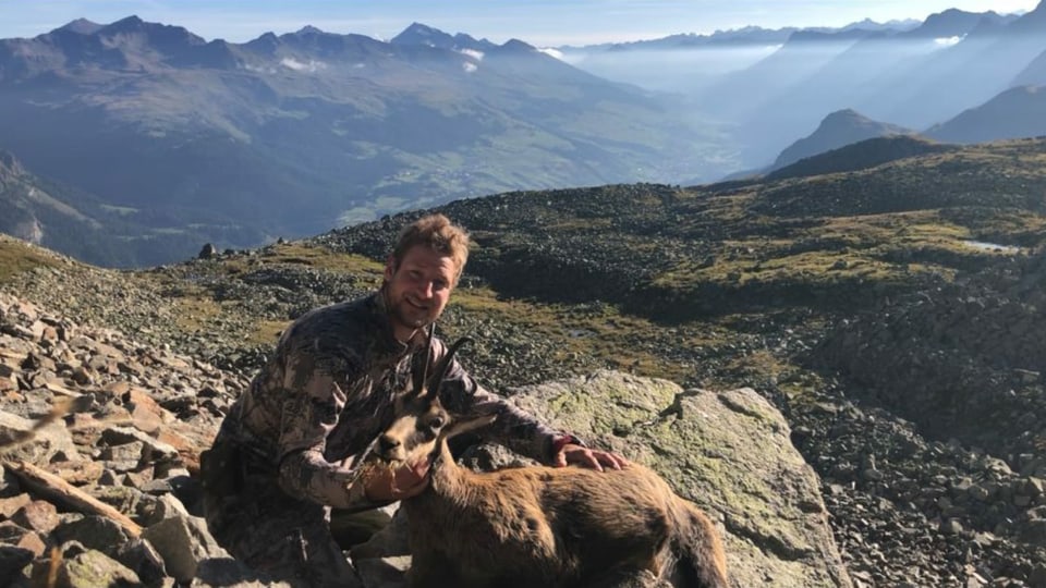 Jäger mit Gämse vor einem Bergpanorama