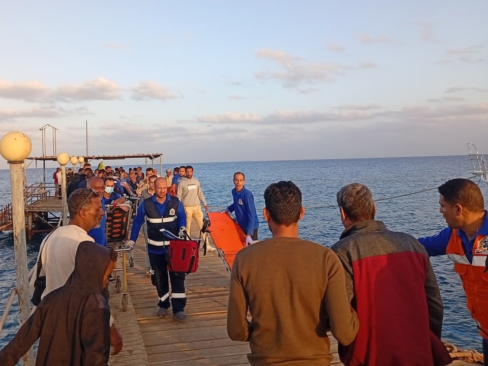 Rettungskräfte auf einem Steg am Meer.