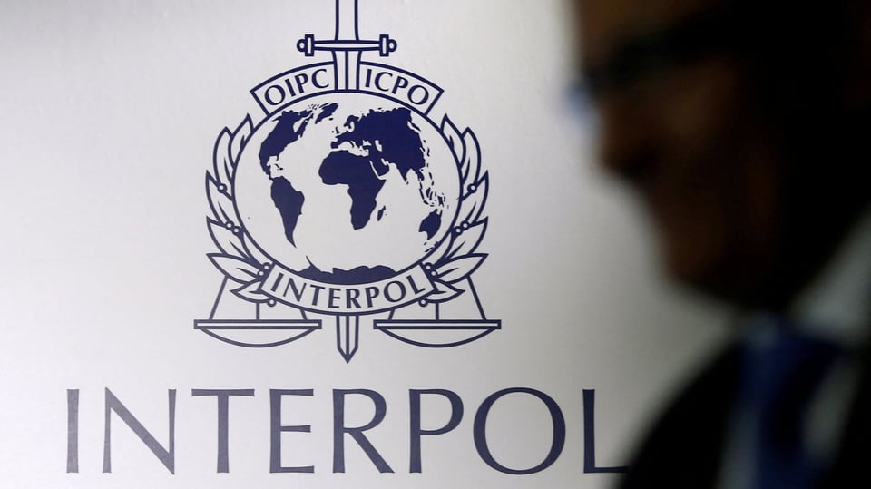 Eine Person geht an einem Interpol-Logo vorbei.