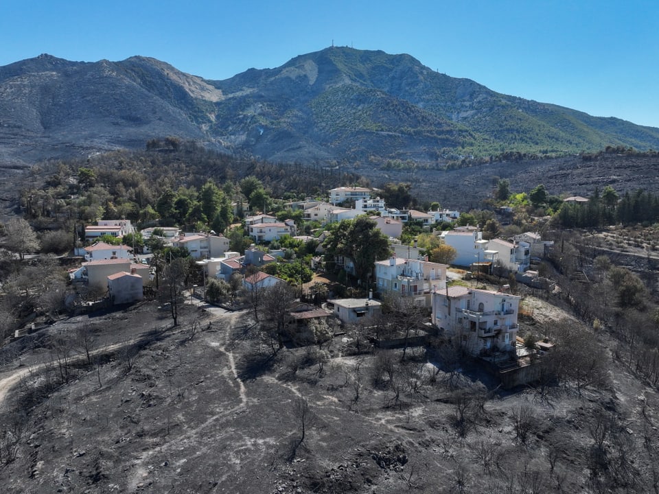 Gebirgsdorf mit durch Waldbrand beschädigtem Umland.