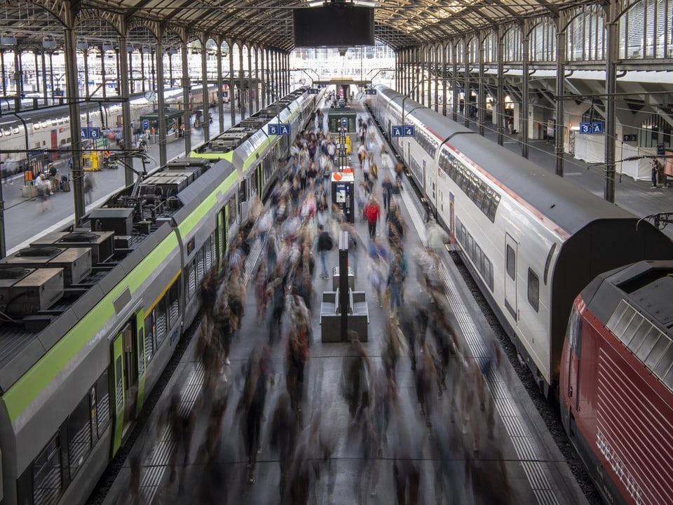 Viele Zugreisende laufen auf einem Perron des Bahnhofs Luzern. Die Reisenden sind unscharf fotografiert..