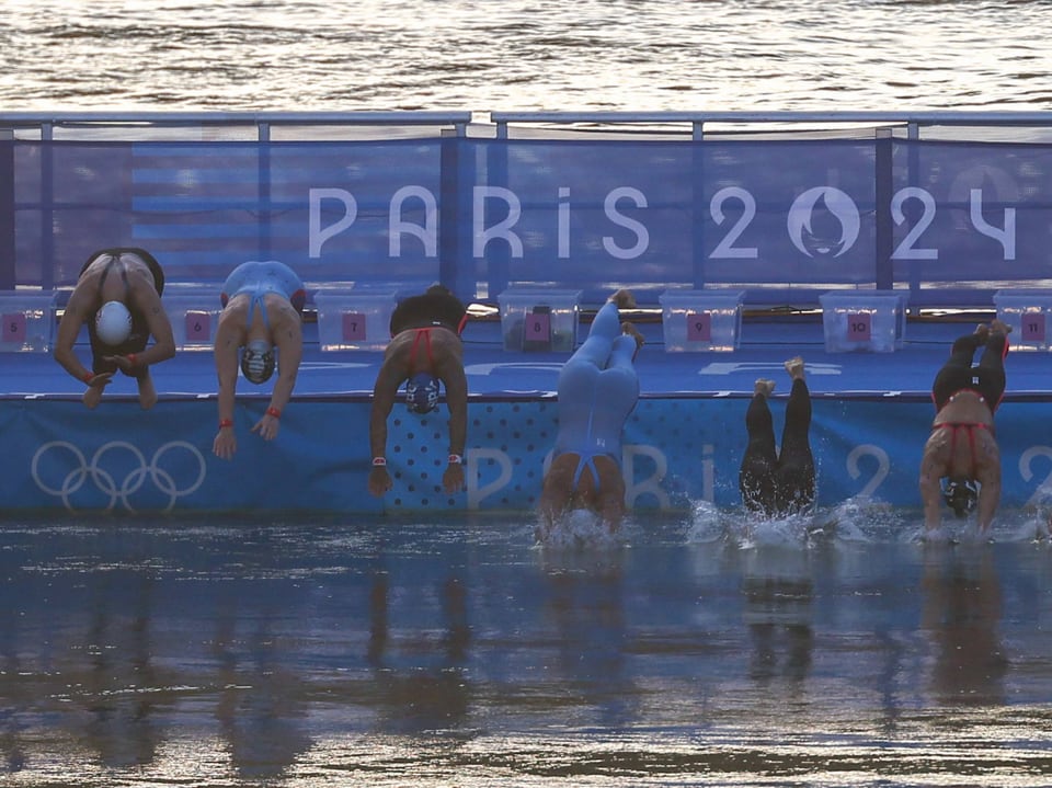 Schwimmer springen ins Wasser bei den Olympischen Spielen Paris 2024.