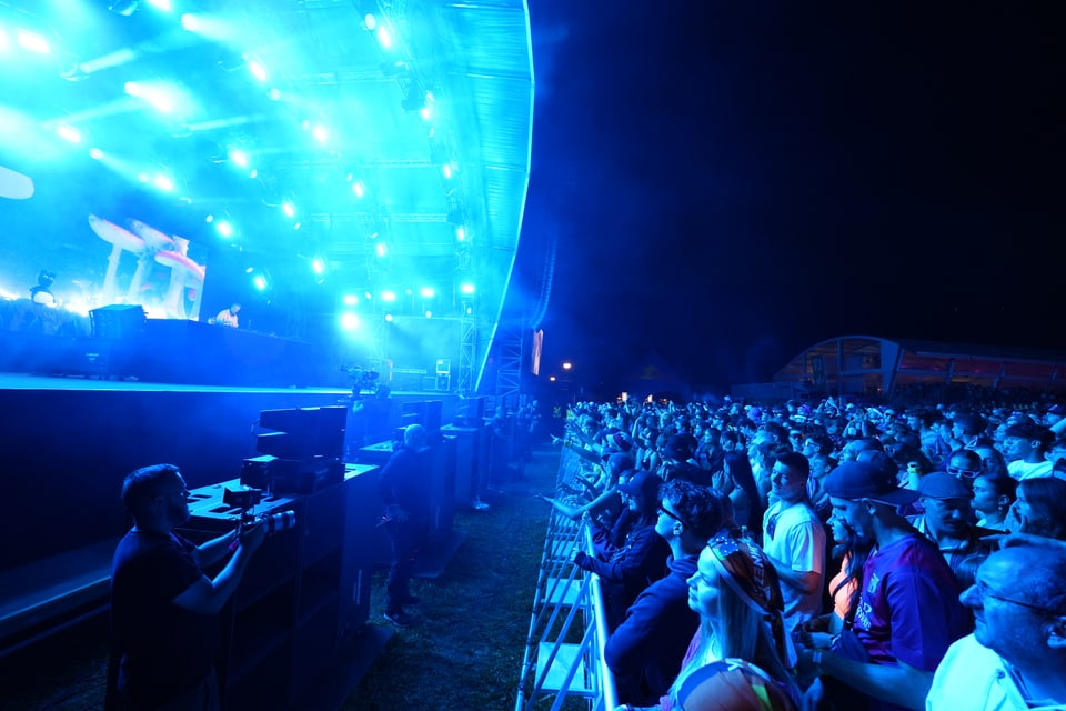 Menschenmenge bei einem Konzert mit blau beleuchteter Bühne am Open Air Lumnezia 2024.