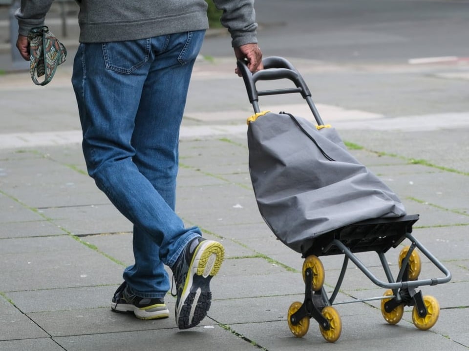 Mann zieht Einkaufstrolley