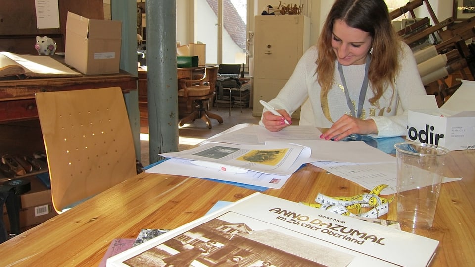 Mädchen schreibt am Tisch, Buch im Vordergrund