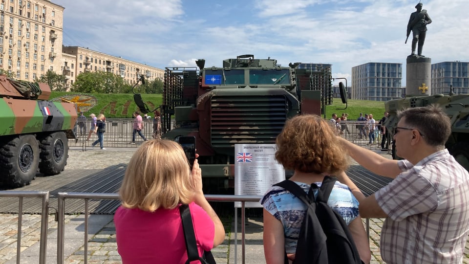 A British tank is inspected by three men.