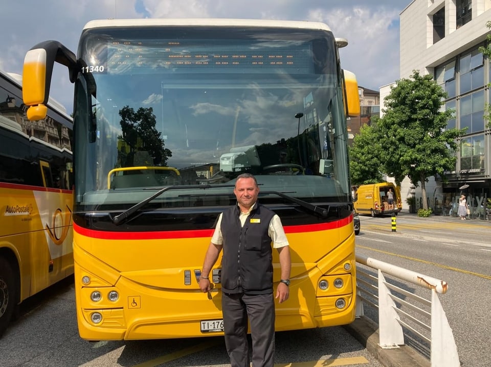 Mann in Uniform vor einem gelben Bus geparkt auf der Strasse.