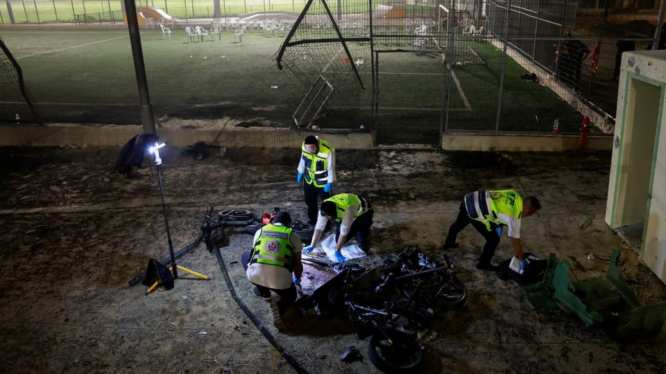 Untersuchung eines Tatorts mit zerstörten Fahrrädern durch vier Menschen in Warnwesten auf einem Sportplatz.
