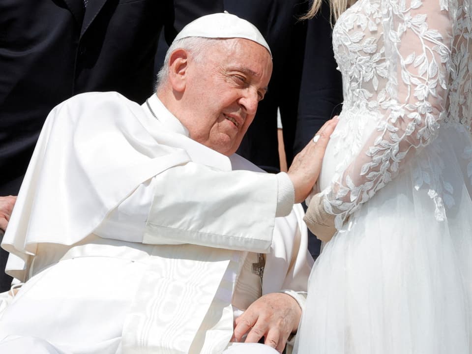 Papst segnet schwangere Frau in weissem Kleid.