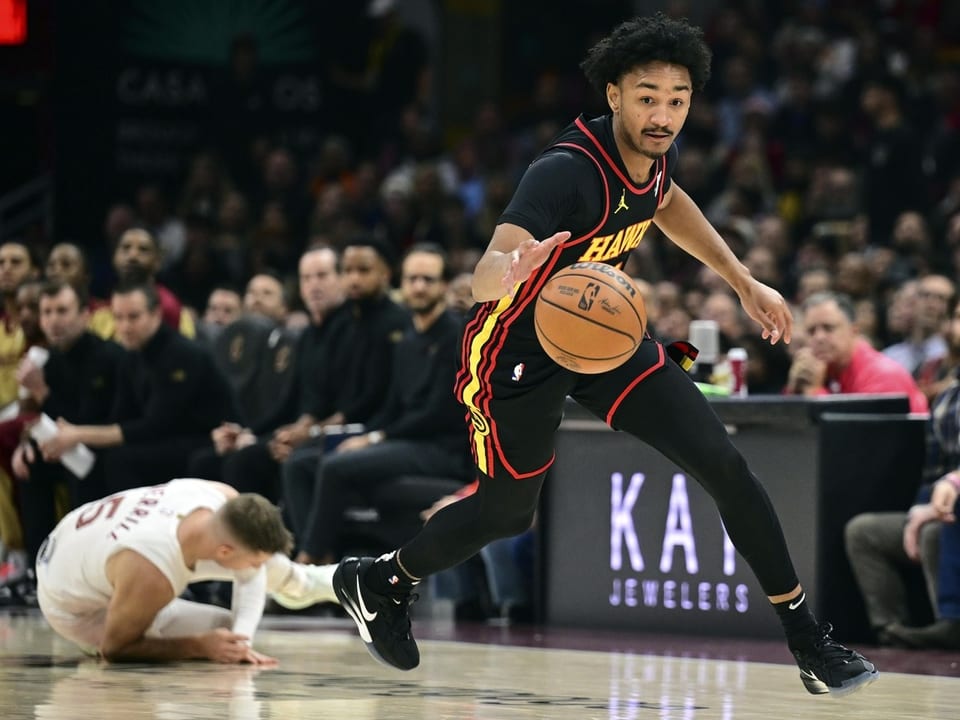 Basketballspieler dribbelt Ball, anderer Spieler am Boden.